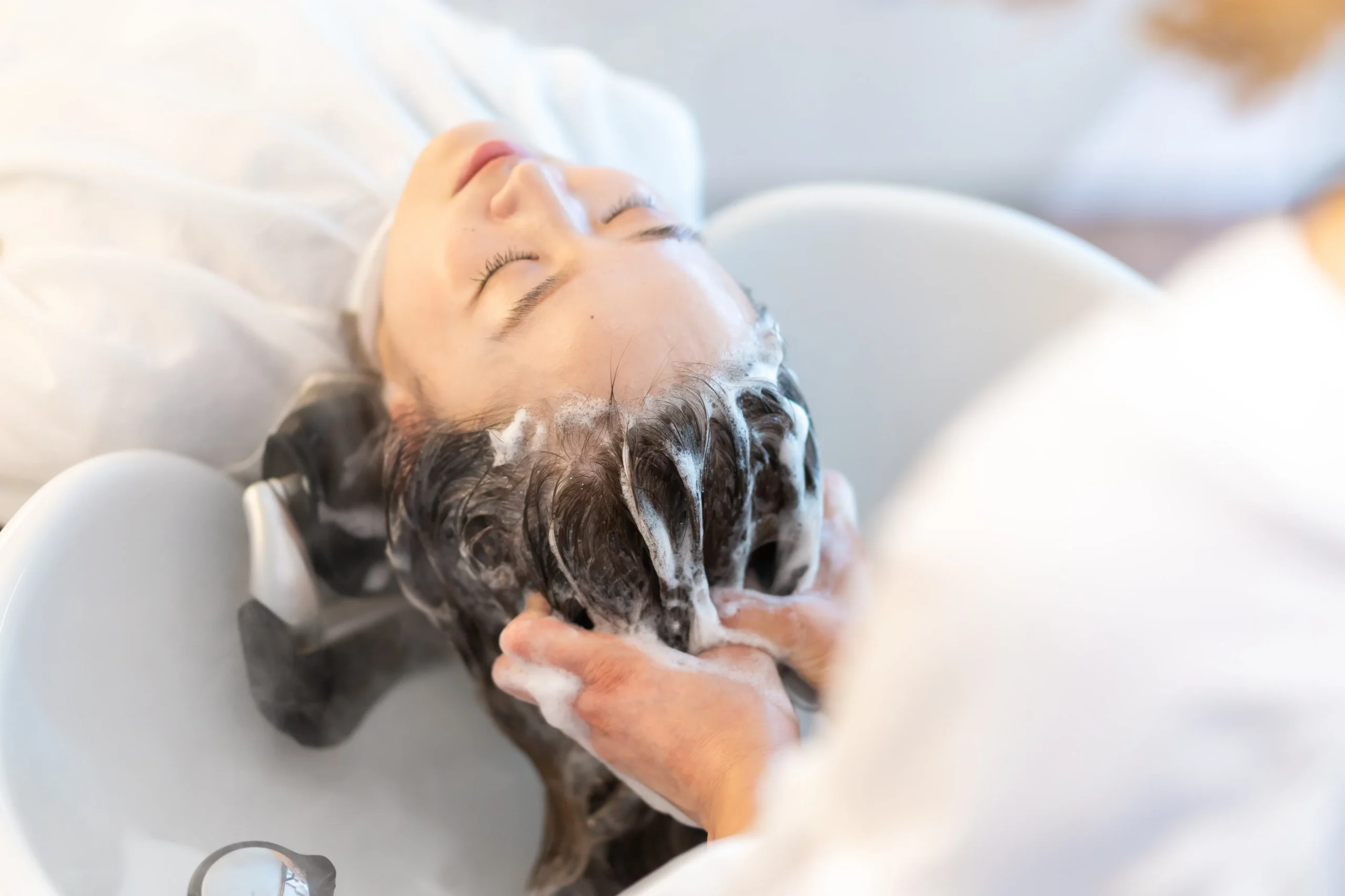 スマートフォンの画面を操作し、広告費の無駄遣いに悩む美容師のイメージ